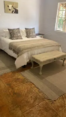 a bedroom with a large bed with a bench on it at Die Kothuis in Malelane