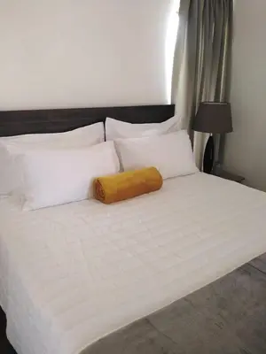 a large white bed with a yellow pillow on it at Arghasbnb in Burgersfort