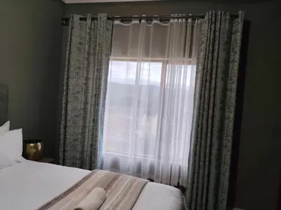 a bedroom with a bed and a window with curtains at Arghasbnb in Burgersfort
