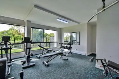 a gym with treadmills and ellipticals in a room with windows at Menlyn apartment with ensuit Regency Hotel in Pretoria