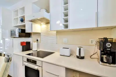a kitchen with white cabinets and a counter top at Menlyn apartment with ensuit Regency Hotel in Pretoria