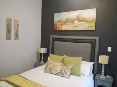 a bedroom with a bed with a painting on the wall at The Garden Inn Guesthouse in Modimolle