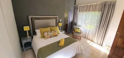 a bedroom with a large bed with yellow pillows at The Garden Inn Guesthouse in Modimolle