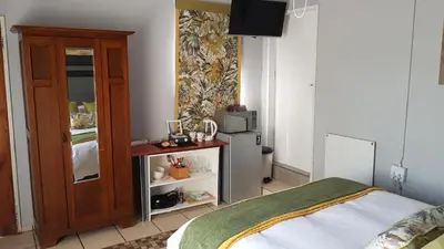 a bedroom with a bed and a cabinet with a microwave at The Garden Inn Guesthouse in Modimolle
