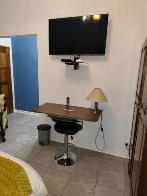 a room with a desk with a television on the wall at The Garden Inn Guesthouse in Modimolle