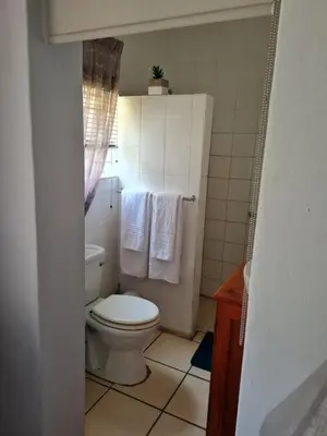 a bathroom with a toilet and towels in it at The Garden Inn Guesthouse in Modimolle