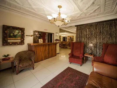 a living room with a couch and chairs and a chandelier at Dunwoodie Travel Lodge in Pretoria