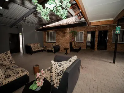 a large living room with couches and chairs at Dunwoodie Travel Lodge in Pretoria
