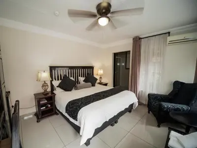 a bedroom with a bed and a ceiling fan at Dunwoodie Travel Lodge in Pretoria