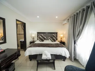 a bedroom with a large bed and a piano at Dunwoodie Travel Lodge in Pretoria