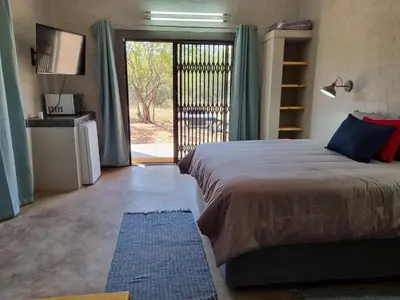 a bedroom with a bed and a sliding glass door at Kolope Lodge in Alldays