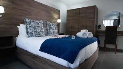 a bedroom with a large bed with a blue blanket at Alveston Manor Boutique Hotel & Spa in Middelburg