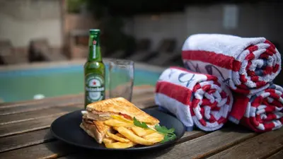 a sandwich and french fries and a bottle of beer on a table at Alveston Manor Boutique Hotel & Spa in Middelburg