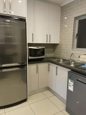 a kitchen with white cabinets and a stainless steel refrigerator at Sunninghill Luxury Spacious Executive Penthouse in Sandton