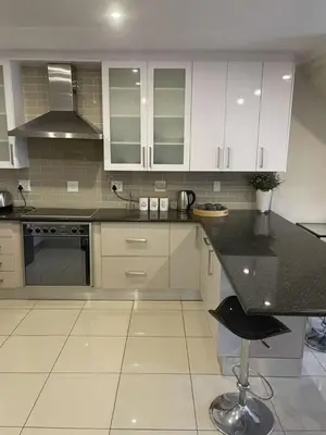 a kitchen with white cabinets and a black counter top at Sunninghill Luxury Spacious Executive Penthouse in Sandton
