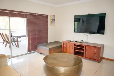 a living room with a ottoman and a large television at Sunninghill Luxury Spacious Executive Penthouse in Sandton