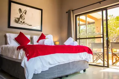 a bedroom with a bed with a red and white blanket at Fairfarren in Hoedspruit