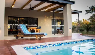 a swimming pool with a chair next to a house at Fairfarren in Hoedspruit