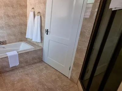 a bathroom with a shower and a tub and a white door at Cussonia Country Home in Tierpoort