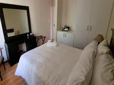 a bedroom with a white bed and a mirror at Cussonia Country Home in Tierpoort