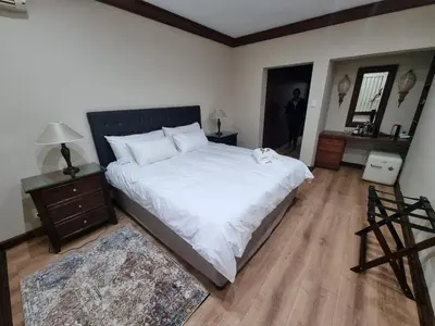 a bedroom with a large white bed and a wooden floor at Cussonia Country Home in Tierpoort