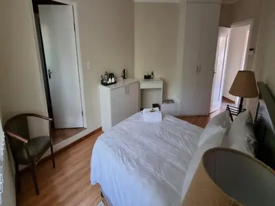 a bedroom with a large white bed and a chair at Cussonia Country Home in Tierpoort