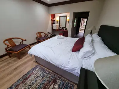 a bedroom with a large white bed and a table at Cussonia Country Home in Tierpoort