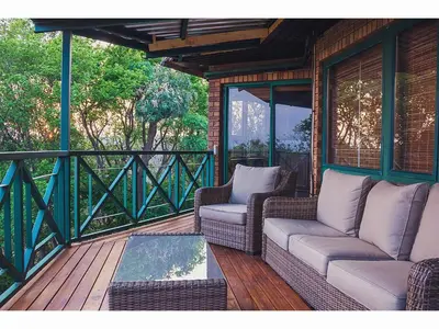 a screened in porch with wicker chairs and a table at Cussonia Country Home in Tierpoort