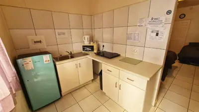 a small kitchen with a refrigerator and a sink at Sheilas Self-Catering Overnight Accommodation in Polokwane
