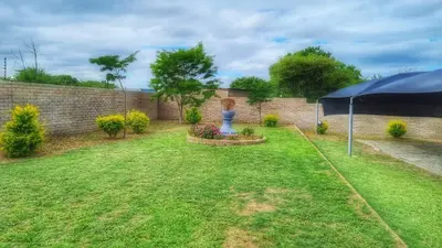 a garden with a blue umbrella in a yard at Sheilas Self-Catering Overnight Accommodation in Polokwane