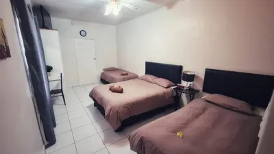 a bedroom with two beds and a table and a clock at Sheilas Self-Catering Overnight Accommodation in Polokwane