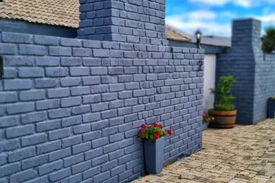 a blue brick wall with a pot of flowers on it at Sheilas Self-Catering Overnight Accommodation in Polokwane