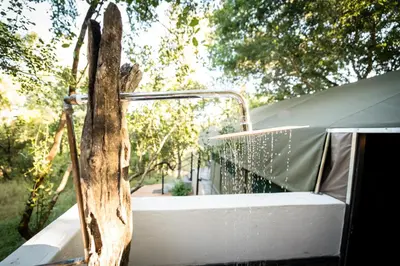 a wooden cross sitting on top of a bed at Umkumbe Bush Lodge - Luxury Tented Camp in Sabi Sand Game Reserve