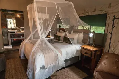 a bedroom with a bed with mosquito netting at Umkumbe Bush Lodge - Luxury Tented Camp in Sabi Sand Game Reserve