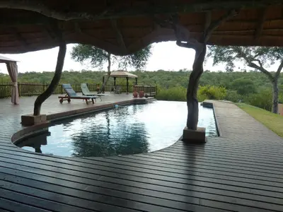 a swimming pool with two chairs and a gazebo at Muweti Bush Lodge in Grietjie Nature Reserve