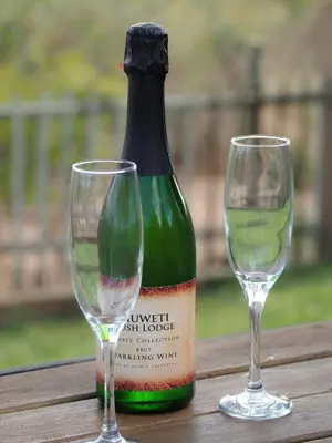 a bottle of wine and two glasses on a table at Muweti Bush Lodge in Grietjie Nature Reserve