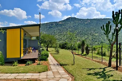 a yellow house with a deck and mountains in the background at SleepOver Moria in Moria