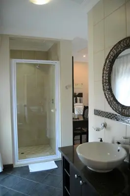 a bathroom with a sink and a glass shower at Glen Marion Guest House in Pretoria