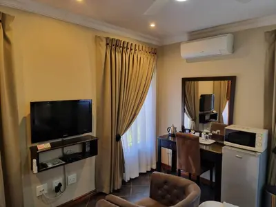 a hotel room with a television and a desk with a chair at Glen Marion Guest House in Pretoria
