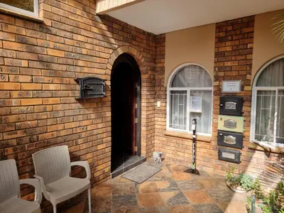 a brick wall with a dog sitting in front of a door at Glen Marion Guest House in Pretoria