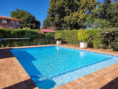 a swimming pool with blue water in a yard at Glen Marion Guest House in Pretoria