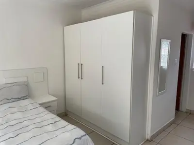 a white bedroom with a bed and a white cabinet at La Fiance Village in Polokwane