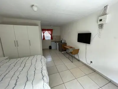 a bedroom with a bed and a table and a television at La Fiance Village in Polokwane