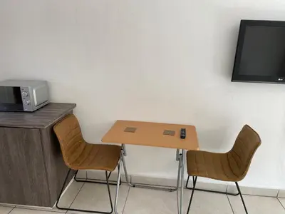 a small table with two chairs and a tv on a wall at La Fiance Village in Polokwane