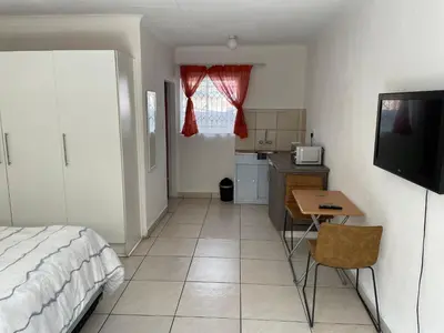 a bedroom with a bed and a table and a kitchen at La Fiance Village in Polokwane