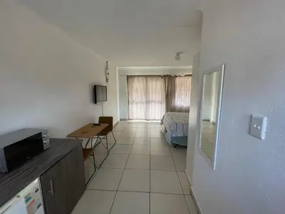 a small room with a bed and a desk in it at La Fiance Village in Polokwane