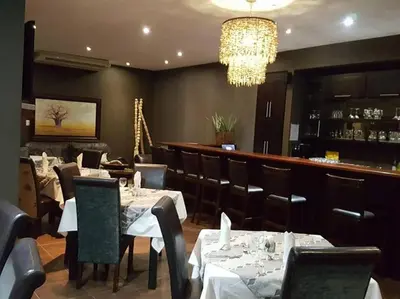 a restaurant with tables and chairs and a chandelier at Kusile Guest House in Burgersfort