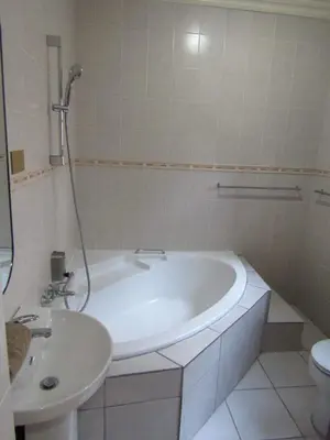 a white bathroom with a tub and a sink at Kusile Guest House in Burgersfort