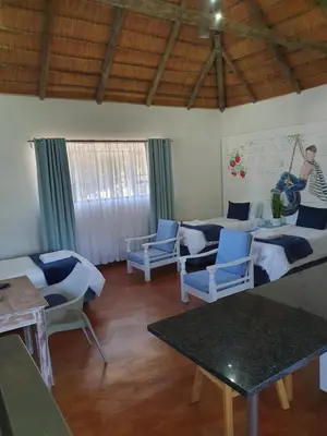 a living room with blue chairs and tables and a man playing a guitar at Pomegranate Selfcatering apartment in Nelspruit