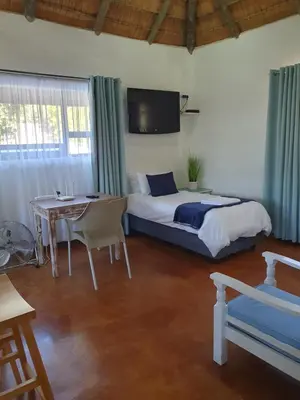 a bedroom with a bed and a table and a tv at Pomegranate Selfcatering apartment in Nelspruit